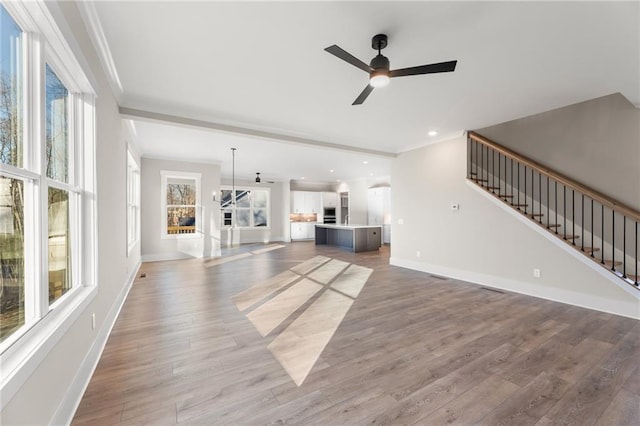 unfurnished living room featuring a fireplace, ceiling fan, hardwood / wood-style floors, and ornamental molding