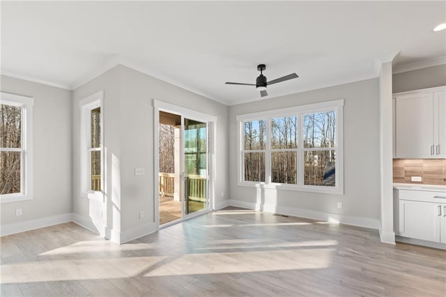 unfurnished dining area featuring plenty of natural light, ceiling fan, and crown molding