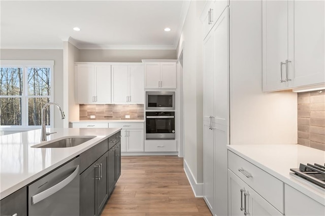 kitchen featuring decorative backsplash, white cabinetry, sink, and appliances with stainless steel finishes