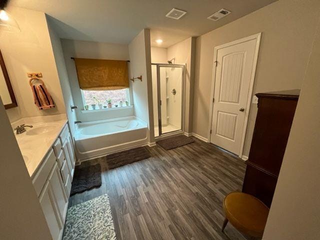 bathroom with wood-type flooring, independent shower and bath, and vanity