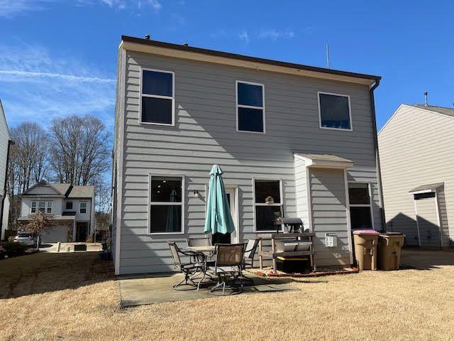 back of property featuring a patio area and a lawn