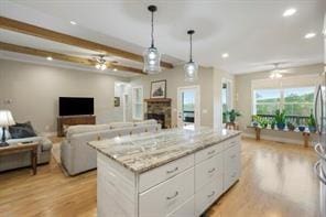 kitchen featuring ceiling fan, white cabinetry, pendant lighting, light hardwood / wood-style floors, and a kitchen island