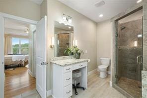 bathroom featuring wood-type flooring, vanity, toilet, and a shower with door