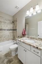 full bathroom featuring vanity, tiled shower / bath combo, and toilet