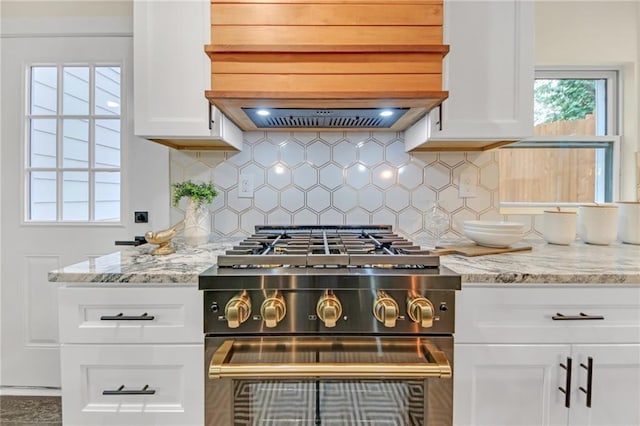 kitchen with light stone counters, white cabinetry, high end stainless steel range, and tasteful backsplash