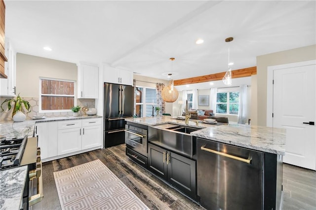 kitchen featuring pendant lighting, dark wood-type flooring, an island with sink, and stainless steel appliances