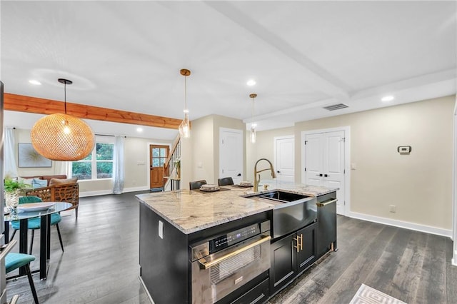 kitchen featuring a center island with sink, decorative light fixtures, stainless steel oven, and dark hardwood / wood-style flooring