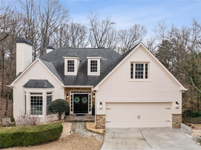 view of front of home with a garage, driveway, brick siding, and roof with shingles