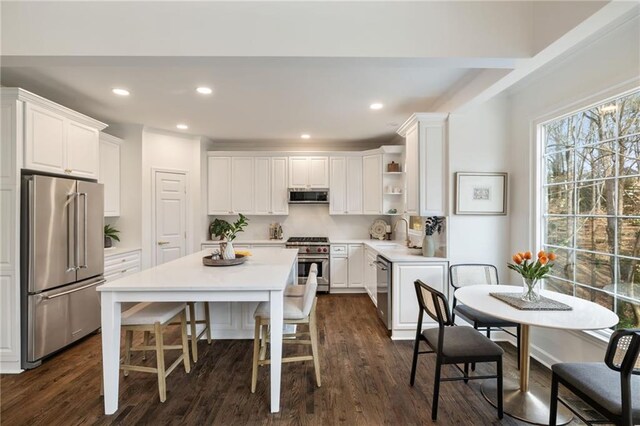 kitchen featuring open shelves, white cabinets, a kitchen island, a sink, and high quality appliances