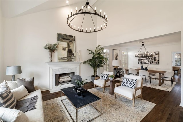 living area with a chandelier, a premium fireplace, dark wood-style flooring, and crown molding