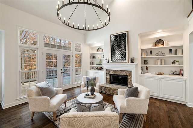 living area featuring french doors, dark wood-type flooring, a fireplace, and built in shelves