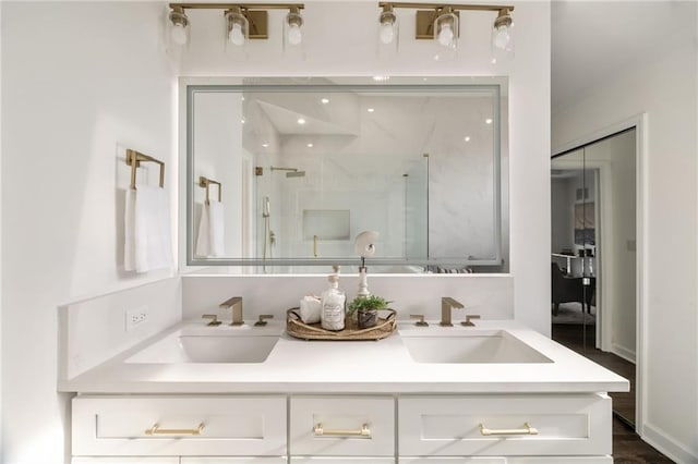 bathroom featuring double vanity, a stall shower, and a sink