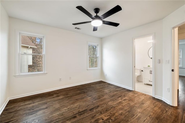 unfurnished bedroom with dark wood-style flooring, visible vents, connected bathroom, ceiling fan, and baseboards