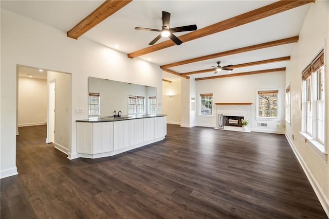 kitchen featuring dark countertops, dark wood-style flooring, a fireplace, and baseboards