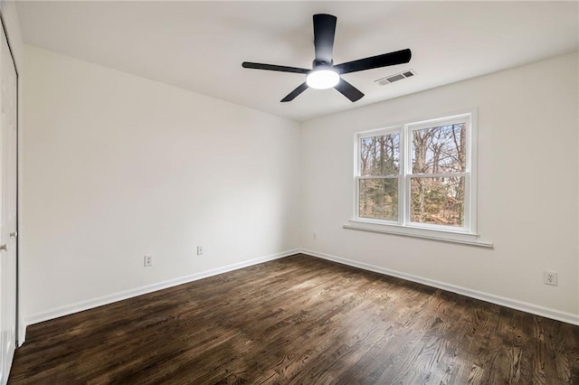 unfurnished room with dark wood-type flooring, visible vents, baseboards, and a ceiling fan