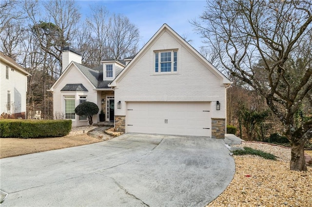 traditional-style home featuring a garage, concrete driveway, stone siding, a chimney, and brick siding