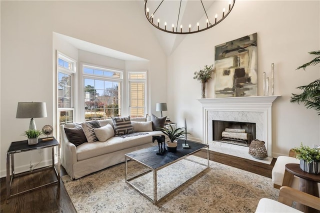 living area featuring a high ceiling, baseboards, a premium fireplace, and wood finished floors