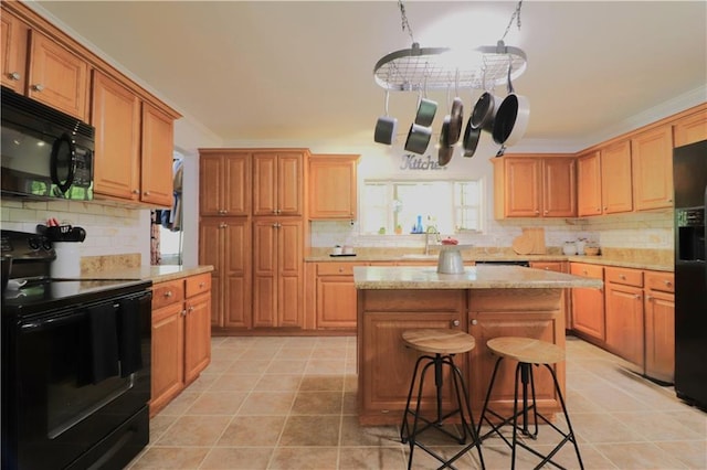 kitchen with crown molding, a kitchen island, a kitchen bar, backsplash, and black appliances