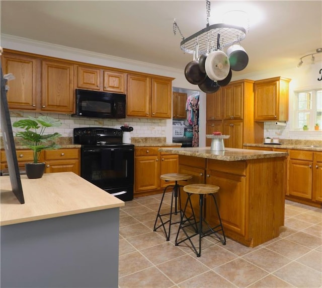 kitchen with a kitchen island, light tile patterned floors, black appliances, and tasteful backsplash