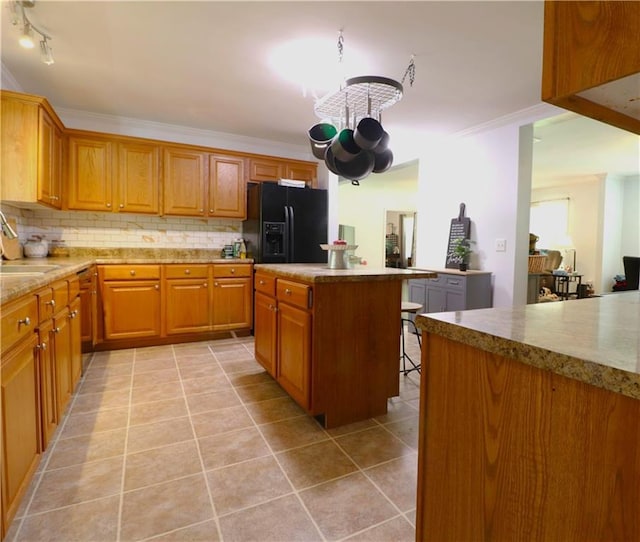 kitchen with a kitchen island, black fridge, backsplash, and light tile patterned flooring