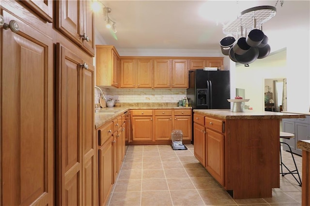 kitchen featuring a kitchen island, a kitchen breakfast bar, a sink, light tile patterned floors, and black fridge