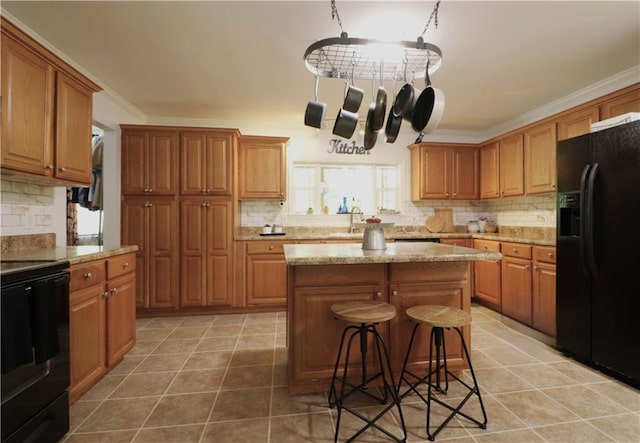 kitchen with crown molding, decorative backsplash, black fridge, and stove