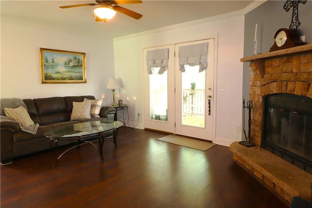 living area featuring a ceiling fan, a fireplace, wood finished floors, baseboards, and ornamental molding