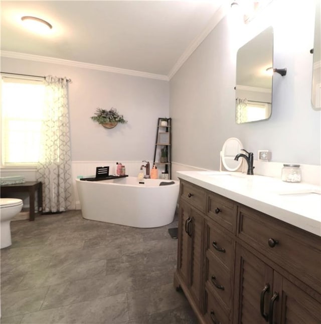 bathroom with wainscoting, vanity, toilet, ornamental molding, and a soaking tub