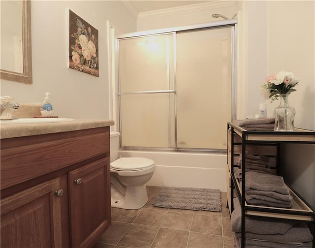 full bathroom with vanity, ornamental molding, tile patterned flooring, toilet, and bath / shower combo with glass door