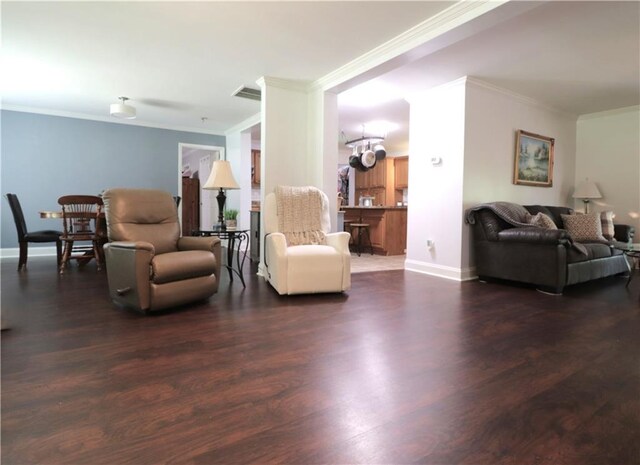 living area featuring crown molding, baseboards, wood finished floors, and visible vents