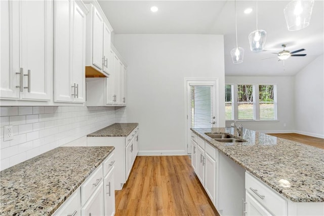 kitchen with white cabinetry, sink, light hardwood / wood-style floors, and decorative light fixtures