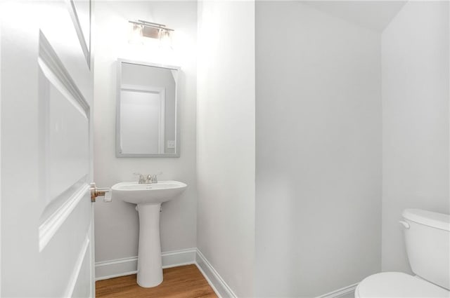 bathroom with hardwood / wood-style flooring, toilet, and sink