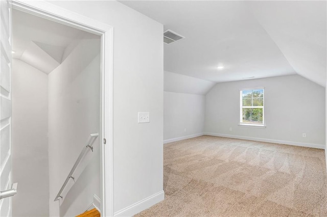 additional living space featuring lofted ceiling and light colored carpet