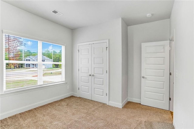 unfurnished bedroom featuring a closet and light carpet