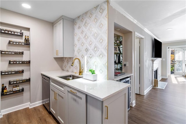 kitchen with dark hardwood / wood-style floors, stainless steel dishwasher, crown molding, and sink