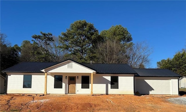 single story home featuring an attached garage, driveway, and metal roof