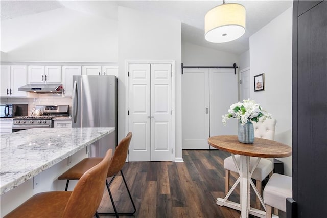 1208 Brandl Dr SW, Marietta, GA 30008 - kitchen with stainless steel appliances, vaulted ceiling, under cabinet range hood, a breakfast bar area, and light stone counters