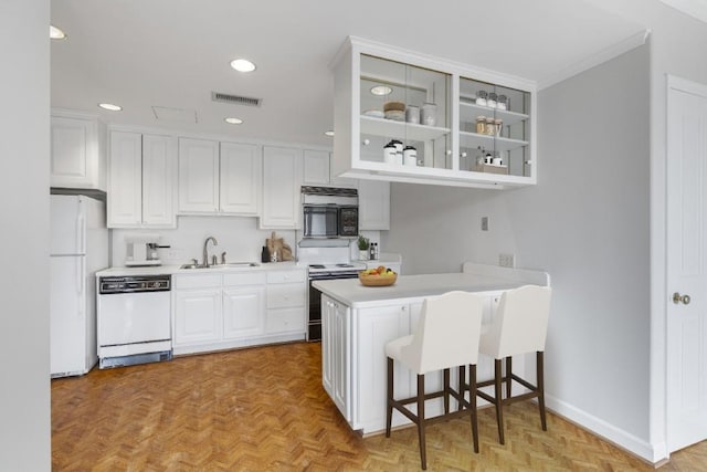 kitchen featuring sink, white appliances, white cabinets, a kitchen bar, and kitchen peninsula