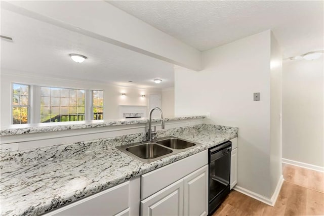 kitchen with a sink, baseboards, black dishwasher, white cabinets, and light wood-style floors