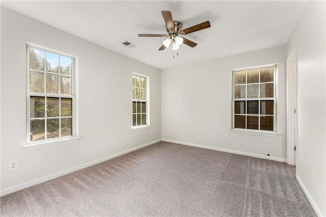 empty room featuring carpet flooring, ceiling fan, visible vents, and baseboards