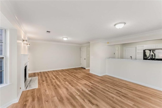 unfurnished living room featuring a fireplace, visible vents, baseboards, light wood-style floors, and ornamental molding