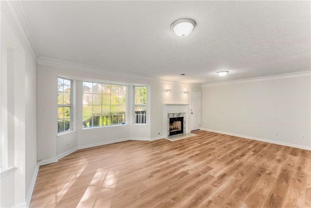 unfurnished living room with light wood-type flooring, a premium fireplace, and crown molding