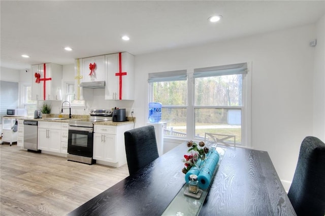 kitchen with a wealth of natural light, light hardwood / wood-style floors, white cabinetry, and appliances with stainless steel finishes