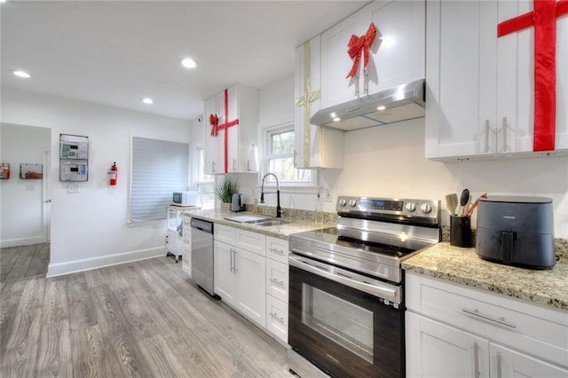 kitchen with light stone countertops, appliances with stainless steel finishes, light wood-type flooring, sink, and white cabinetry