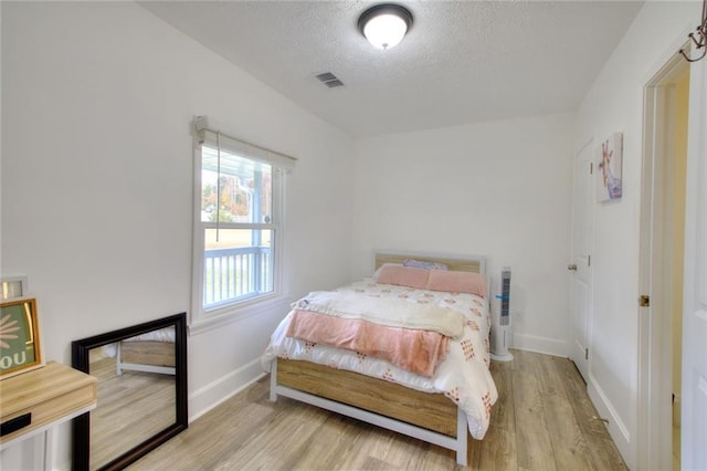 bedroom with light hardwood / wood-style floors and a textured ceiling