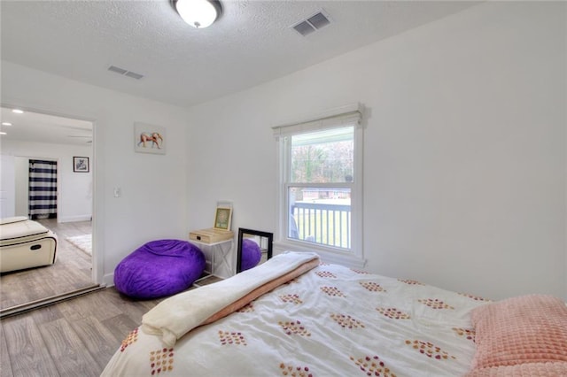 bedroom with a textured ceiling and hardwood / wood-style flooring