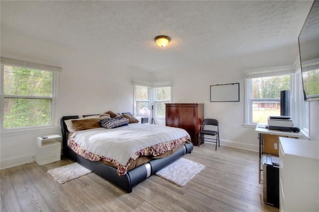 bedroom with a textured ceiling and light wood-type flooring