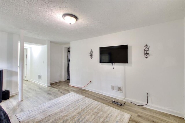 unfurnished living room featuring light hardwood / wood-style floors and a textured ceiling