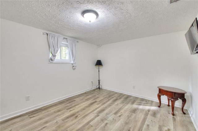 unfurnished room with a textured ceiling and light hardwood / wood-style flooring