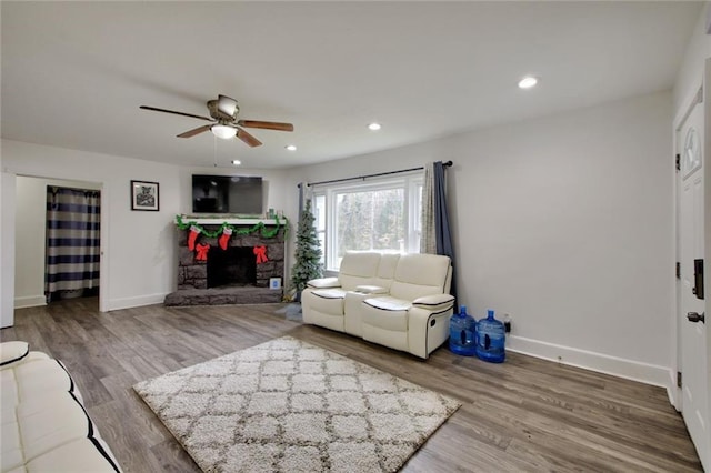 living room featuring ceiling fan, wood-type flooring, and a fireplace